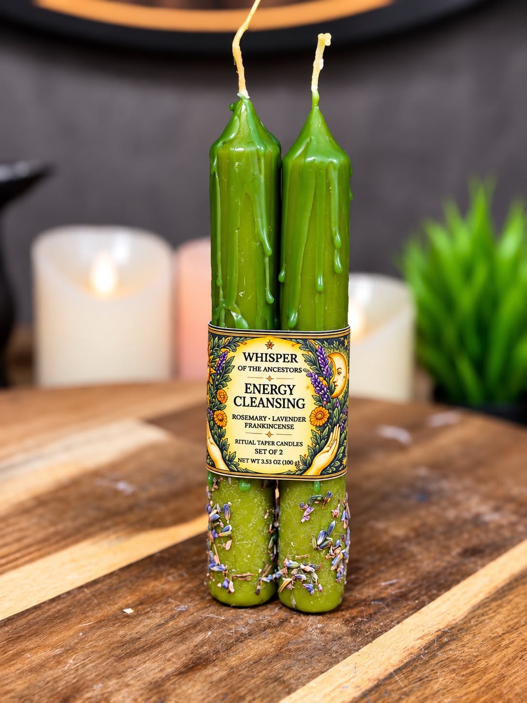 Pair of green Energy Cleansing ritual taper candles with wax drips, dried lavender botanicals and a paper band label
