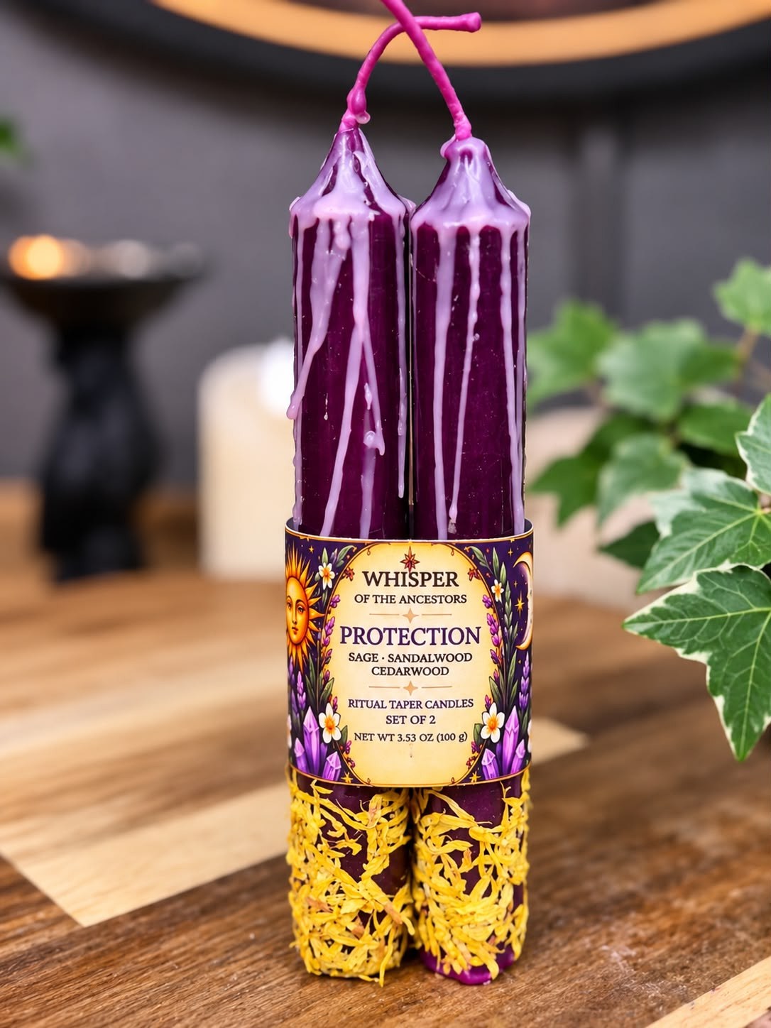 Pair of deep purple Protection ritual taper candles with lavender wax drips and dried yellow petals at the bases, held together by a cream and purple label band